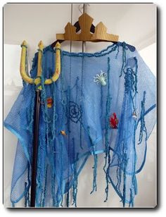 there is a blue shawl hanging on the wall with beads and other things around it