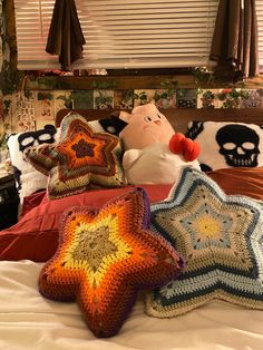 three crocheted pillows on a bed with two stuffed animals in the middle and one pillow that is shaped like a star