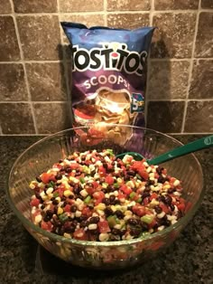 a bowl filled with beans and corn next to a bag of tortilla chips