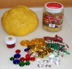 a table topped with lots of different types of beads next to a jar of candy