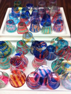 there are many different colored glass bowls on the trays and one is filled with candy