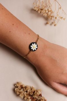 a woman's arm with a flower bracelet on it