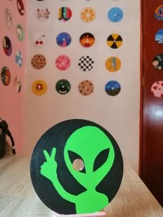 an alien head sitting on top of a wooden table next to a wall covered in magnets