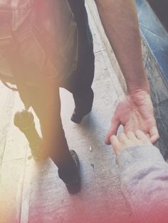 two people holding hands while walking down the street