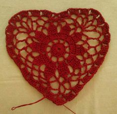 a red crocheted heart on a white surface