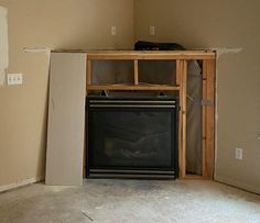 an empty room with a fireplace in the middle and unfinished walls on either side,