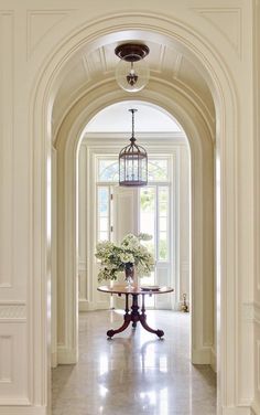 an archway leading to a dining room and entry way with potted plants on the table