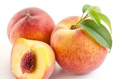 two peaches with one cut in half and the other whole, on a white background