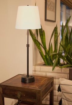 a lamp on a small table next to a potted plant in a living room