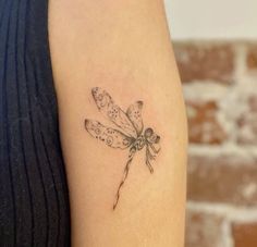 a small dragonfly tattoo on the arm