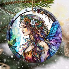 a glass ornament with a woman's face and wings in the snow