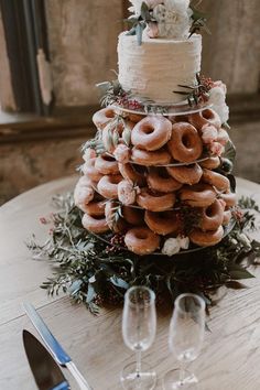 a wedding cake made out of doughnuts on top of a table with wine glasses