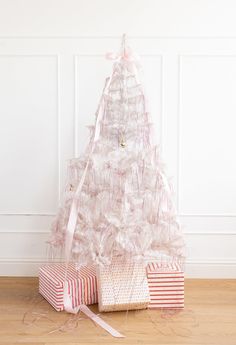 a white christmas tree sitting next to two wrapped presents on top of a wooden floor