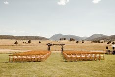 an outdoor ceremony set up in the middle of a field with mountains in the background