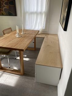 a wooden table sitting next to a window in a room with white walls and tile flooring