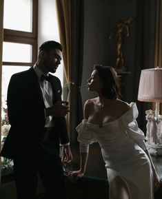 a man in a tuxedo standing next to a woman in a white dress