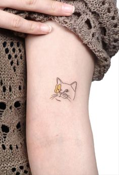 a woman's arm with a cat tattoo on the left side of her arm