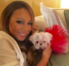 a woman holding a small white dog on top of a couch in a living room