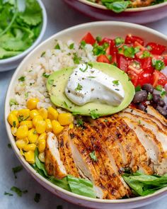 a bowl filled with chicken, rice, corn and avocado on top of it