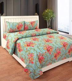 a bed with a flowered bedspread and matching pillow cases in a room