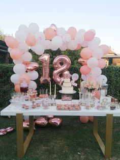 a table topped with pink and white balloons in the shape of number twenty two surrounded by other items