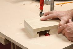 a man working on a piece of wood with a router and drill bit in it