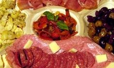 an assortment of meats and cheeses are arranged on a platter with olives