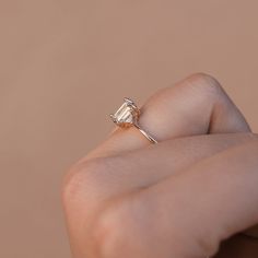 a woman's hand holding an engagement ring in front of her face with the diamond setting on it