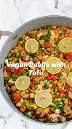 a pan filled with vegetables and lemons on top of a white marble countertop