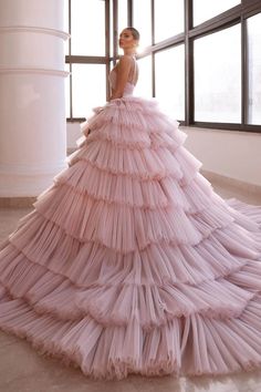 a woman in a long pink dress standing next to a large window