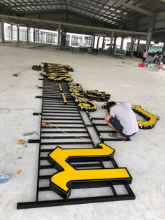 a man kneeling down on top of a black and yellow sign in the middle of a building