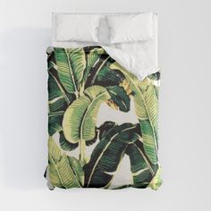 a bed with white sheets and green leaves on it