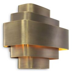 a wall light that is on the side of a white wall and has a gold colored finish