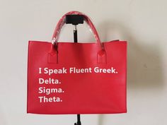 a red bag with white writing on it that says i speak flunt greek delta stigma thea