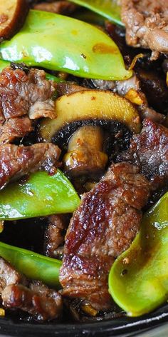 meat and vegetables are being cooked in a skillet