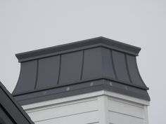 the top of a white building with a black roof and gray shingles on it