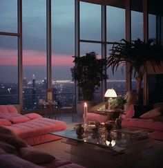 a living room filled with pink couches and a table in front of large windows