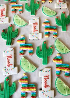 decorated cookies are arranged in the shape of cactus and limes