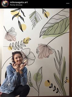 a woman kneeling on the ground in front of a wall with flowers painted on it