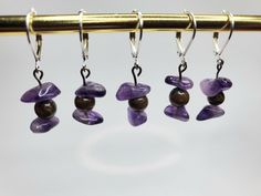 three pairs of earrings hanging from a metal rod with beads and stones in them on hooks