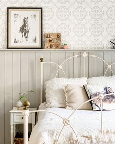 a white bed sitting in a bedroom next to a wall with pictures on it's sides