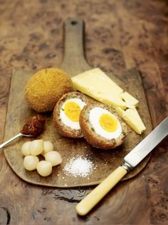 an assortment of food on a plate with a knife next to it and some eggs in the middle