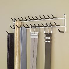 several belts hanging on a wall with hooks