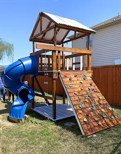 there is a blue slide next to a wooden play structure in the yard with people standing around it