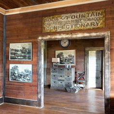 an old fashioned wooden room with pictures on the wall and a clock hanging from the ceiling