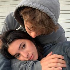 two people hugging each other in front of a house