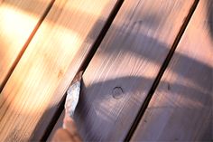 a person is pointing at something on a wooden surface with their finger in the wood