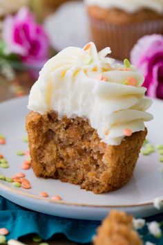 a cupcake with white frosting and sprinkles on a plate