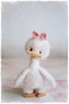 a white stuffed bird with a pink bow on its head