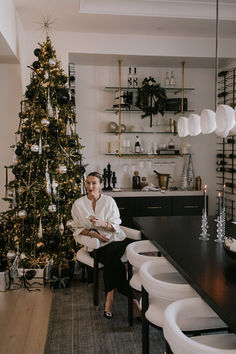 a woman sitting at a table in front of a christmas tree